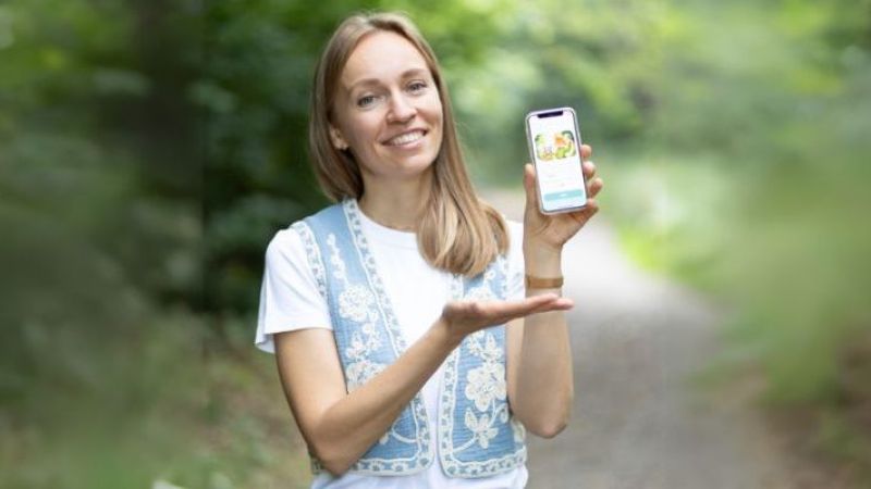 Die Gründerin zeigt ihre App auf dem Handy