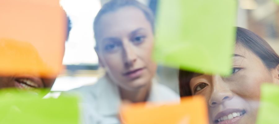 Des jeunes écrivant sur des Post-it collés sur une paroi vitrée.