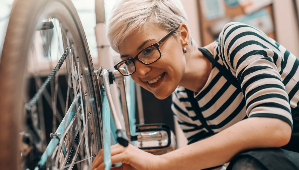 Une femme examine le pneu arrière d'un vélo posé sur son guidon.