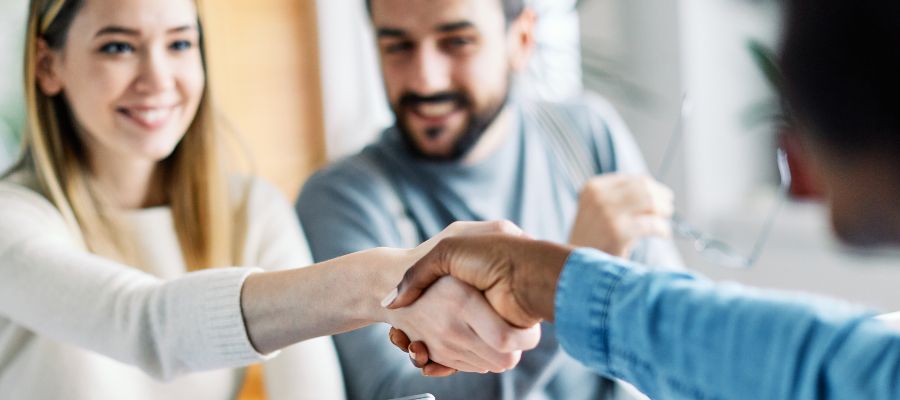 A woman and another person are shaking hands.