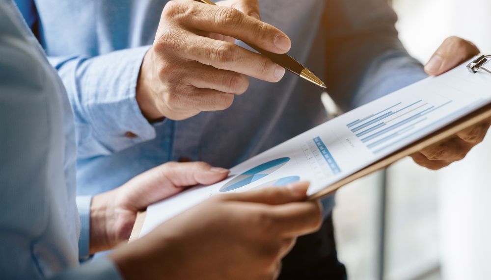 Gros plan sur deux paires de mains tenant un bloc-notes sur lequel figure un schéma. Une main pointe le support du doigt à l'aide d'un stylo.