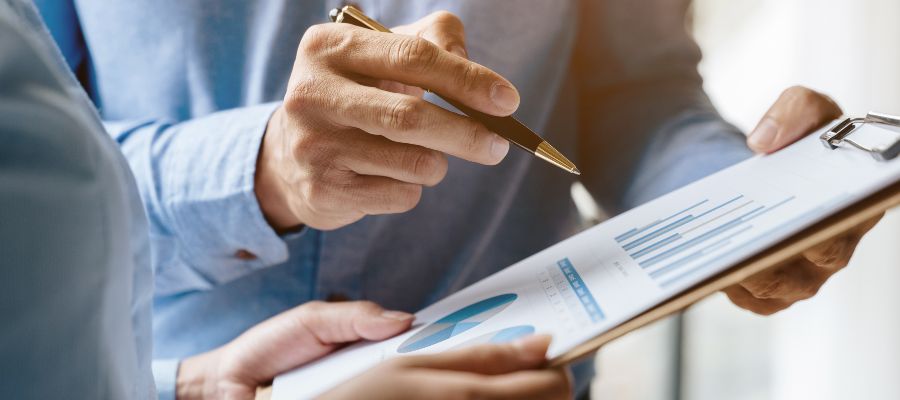 Gros plan sur deux paires de mains tenant un bloc-notes sur lequel figure un schéma. Une main pointe le support du doigt à l'aide d'un stylo.