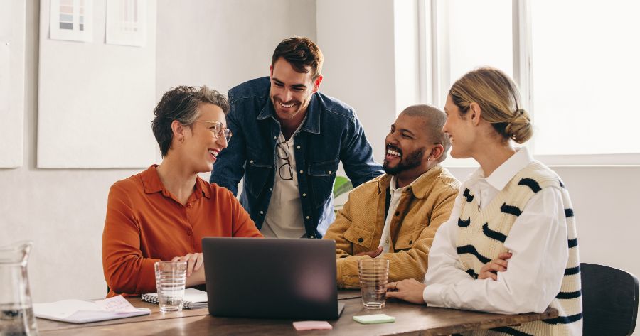Several people sitting at a table with a laptop, chatting
