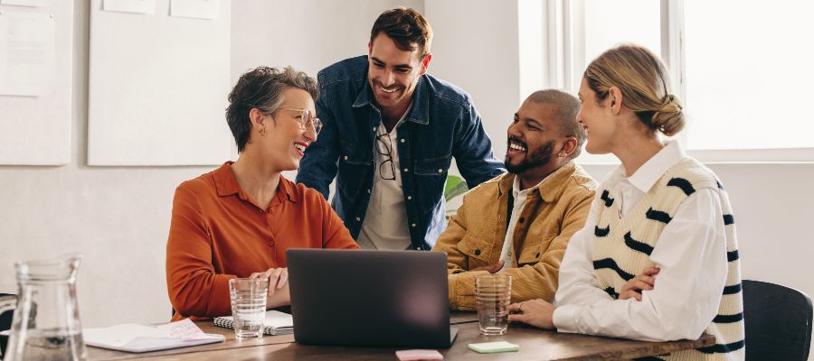 Plusieurs personnes sont assises à une table avec un ordinateur portable et discutent