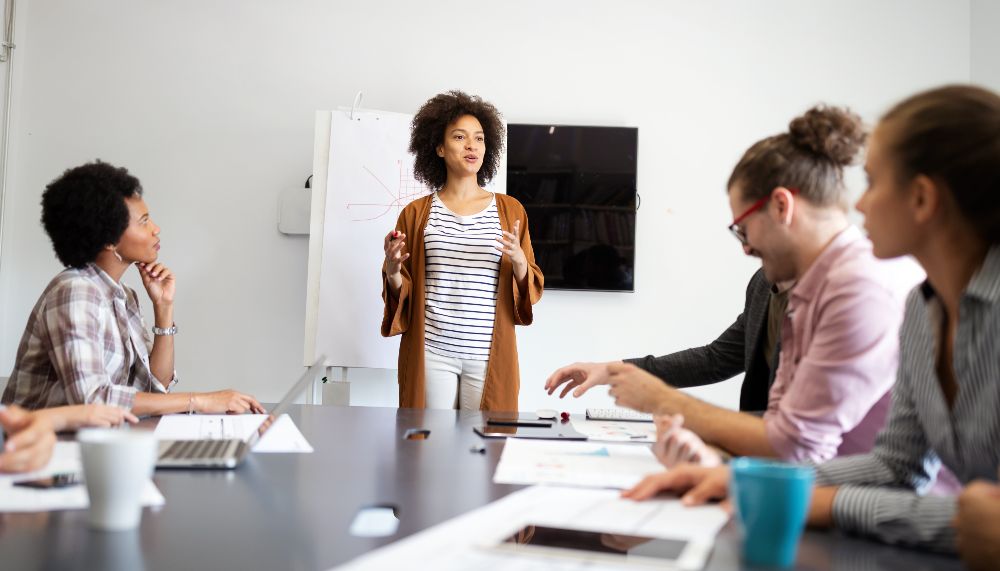Plusieurs personnes, debout et assises, discutent autour d'une table