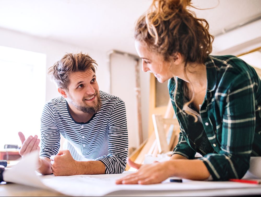 A man and a woman are looking at a map together at a table.