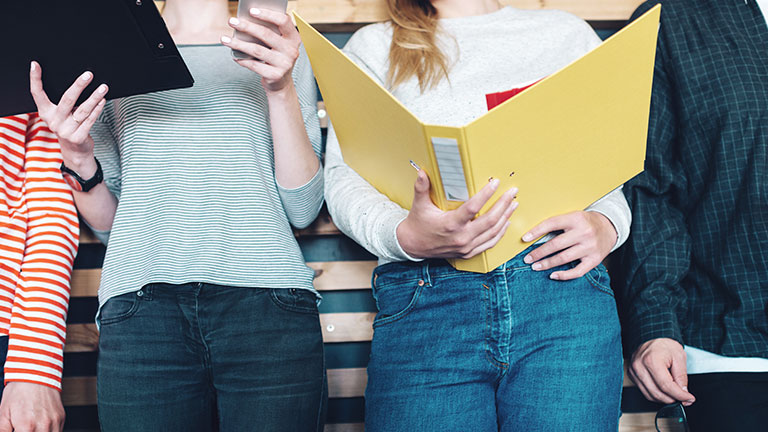 Close-up of women with clipboard, smartphone and folder.