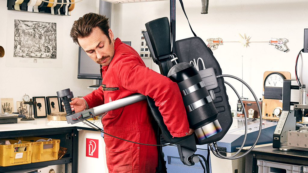 Ein Mann probiert in einer Werkstatt ein Jet-Pack aus.