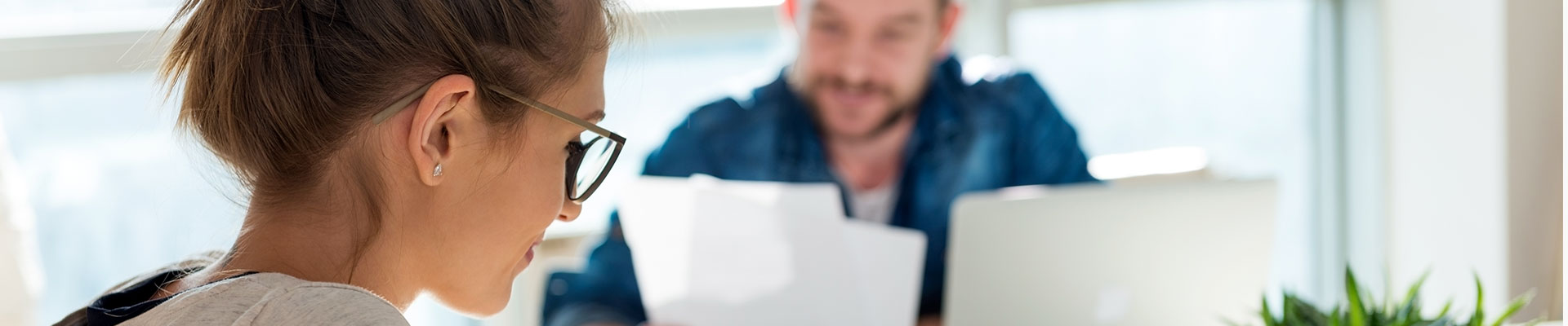 A woman and a man in the background read documents.