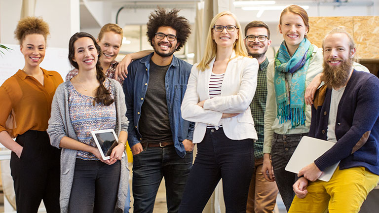 Young men and women stand side by side in a row, smiling or laughing.