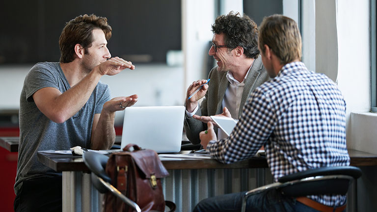 Three men are sitting together and are talking to eachother. 