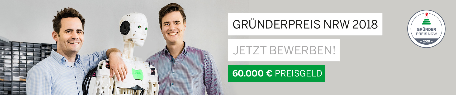 Zwei Männer posieren mit einem androiden Roboter.