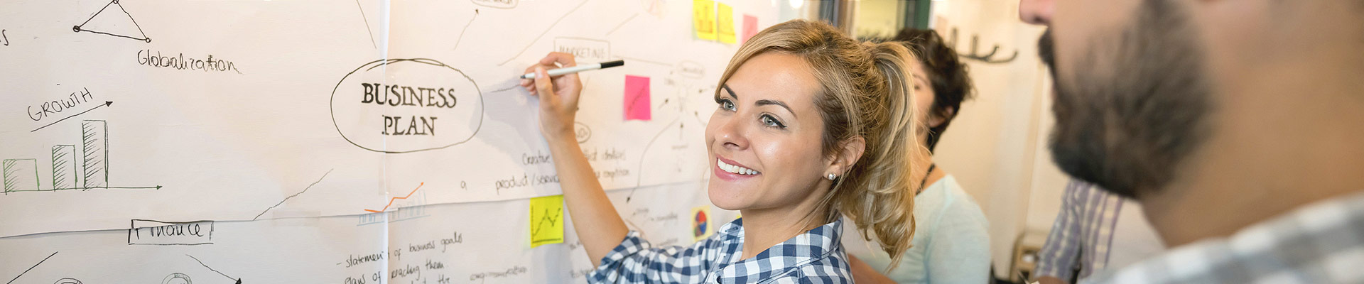 A woman creates a business plan on a metaplan wall.