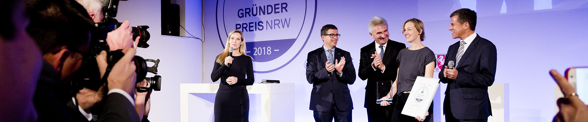 Minister Andreas Pinkwart mit Gewinnern auf Bühne vor Presse