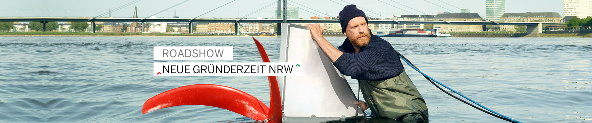 Mann mit Mütze steht im Wasser und hält eine Gerät mit Schraube