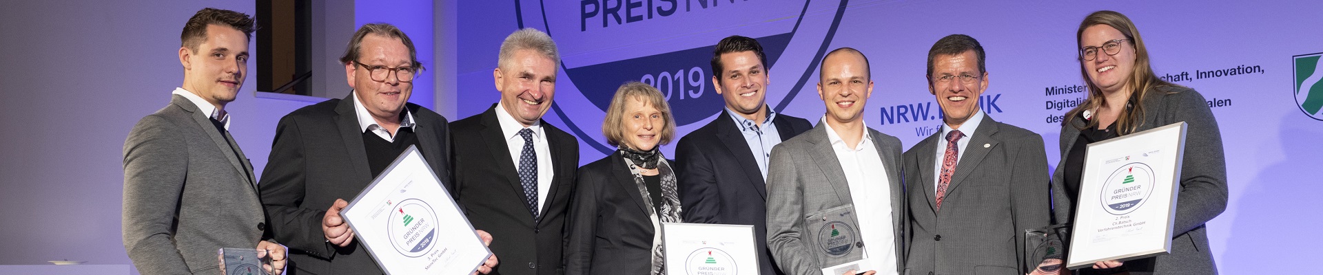 Minister Andreas Pinkwart steht mit den Gewinnern des Gründerpreises auf der Bühne