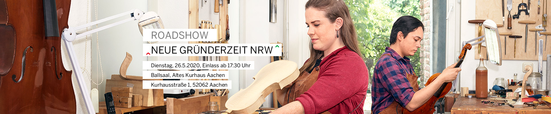 Un luthier tient un violon dans son atelier.