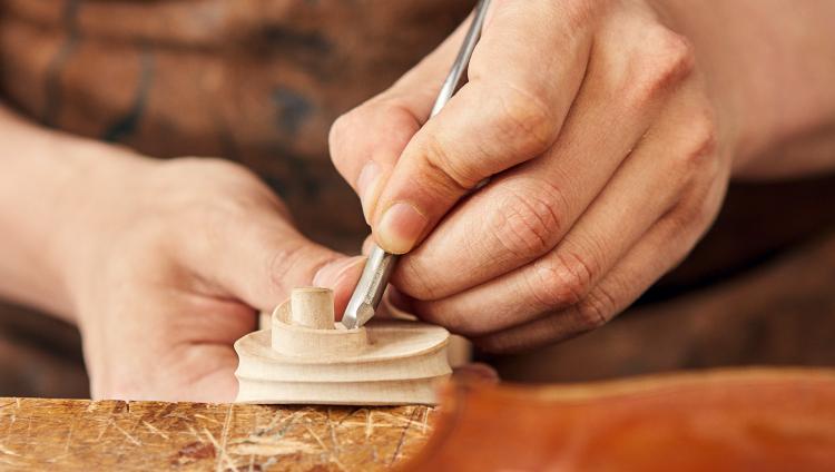 Judith Huppertz works on an element of a violin. 