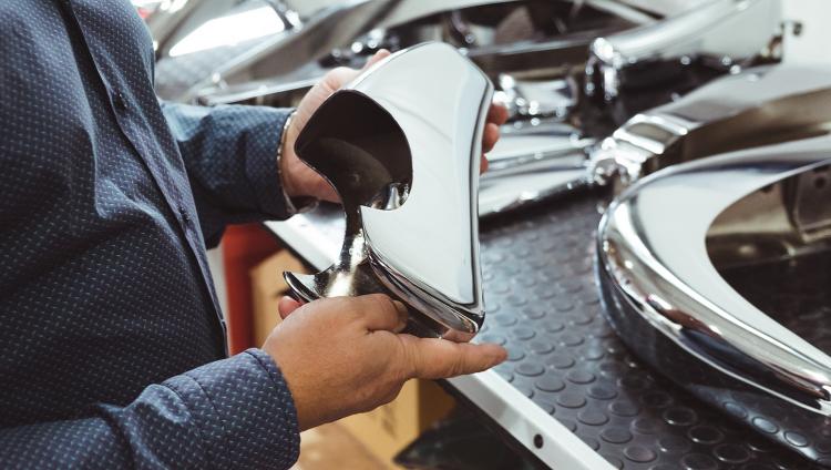 Andreas Mayer hält ein Bauteil eines Autos in der Hand