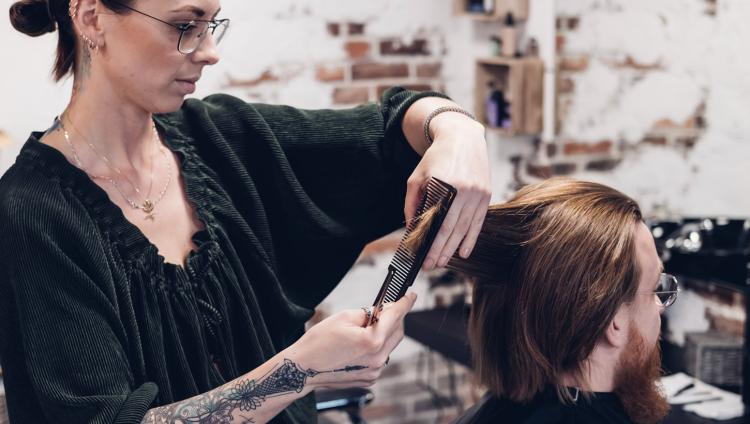 Eine Frau schneidet einem Mann die Haare.