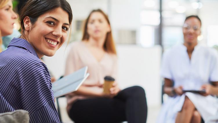 Focus of a young woman, who sits in a chair circle.