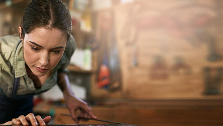 A young woman puts an angle to a piece of wood.