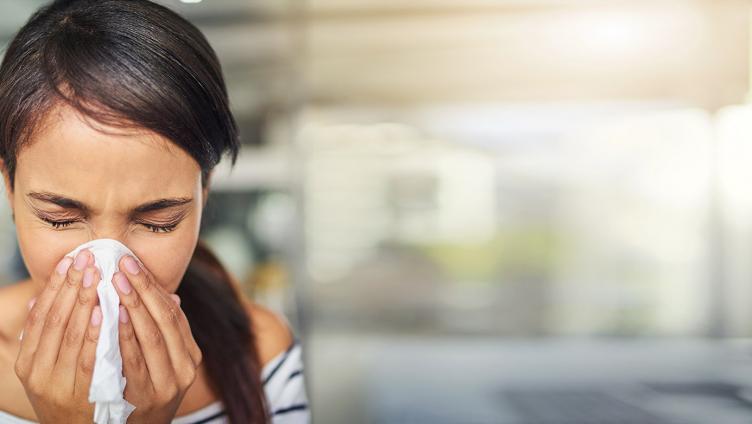 A woman puffs her nose in a handkerchief.