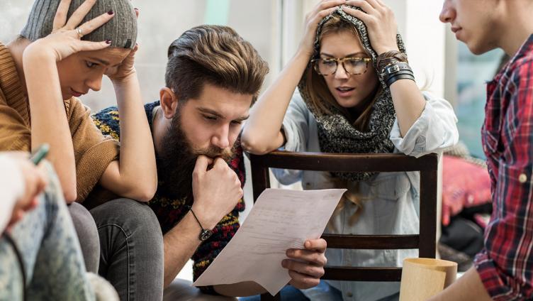 A group of young people sit together and ponders over a piece of paper.