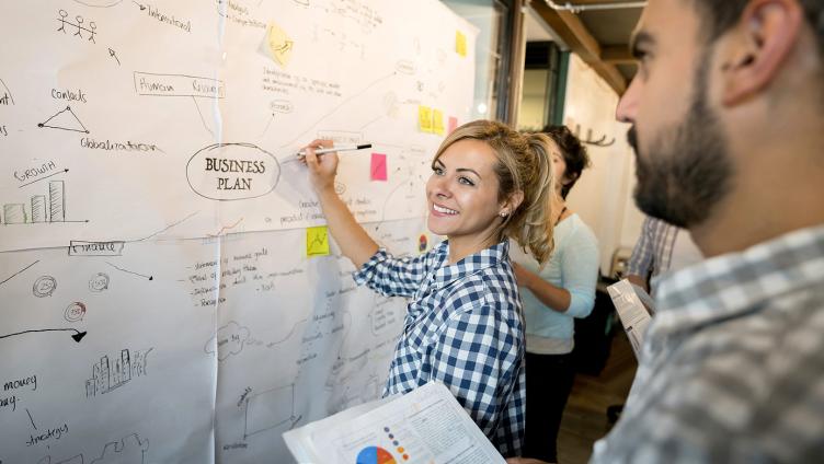 A woman creates a business plan on a metaplan wall.