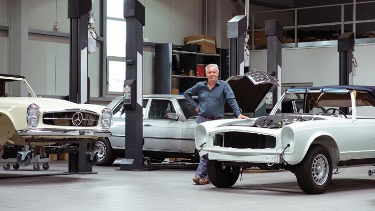 Andreas Meyer steht in der Werkstatt neben einem Auto