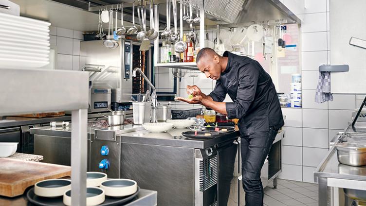 Anthony Sarpong est dans la cuisine et prépare un repas.
